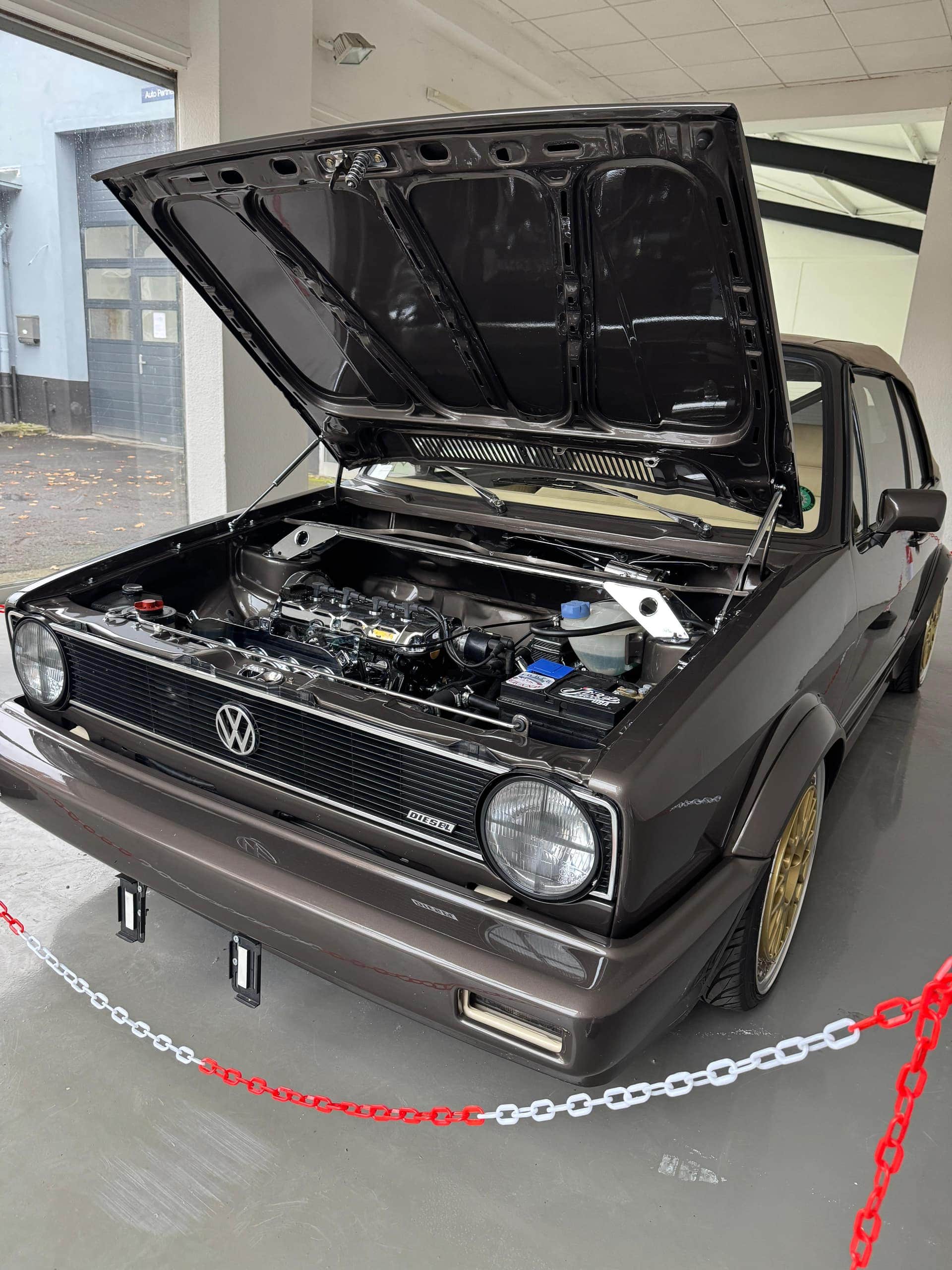 Brauner VW Golf 1 Cabrio mit geöffneter Motorhaube und Blick in den Motorraum