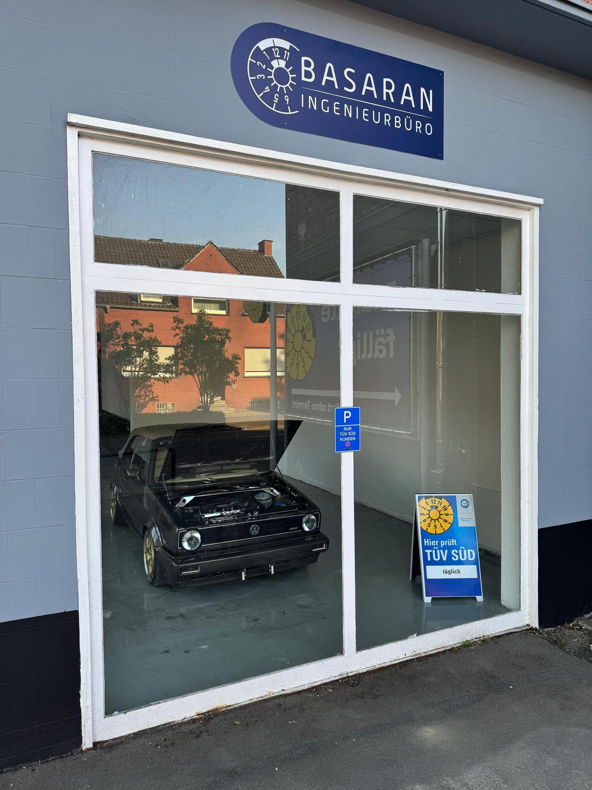 Schaufenster der Prüfhalle mit Schriftzug Basaran Ingenieurbüro und VW Golf Cabrio dahinter