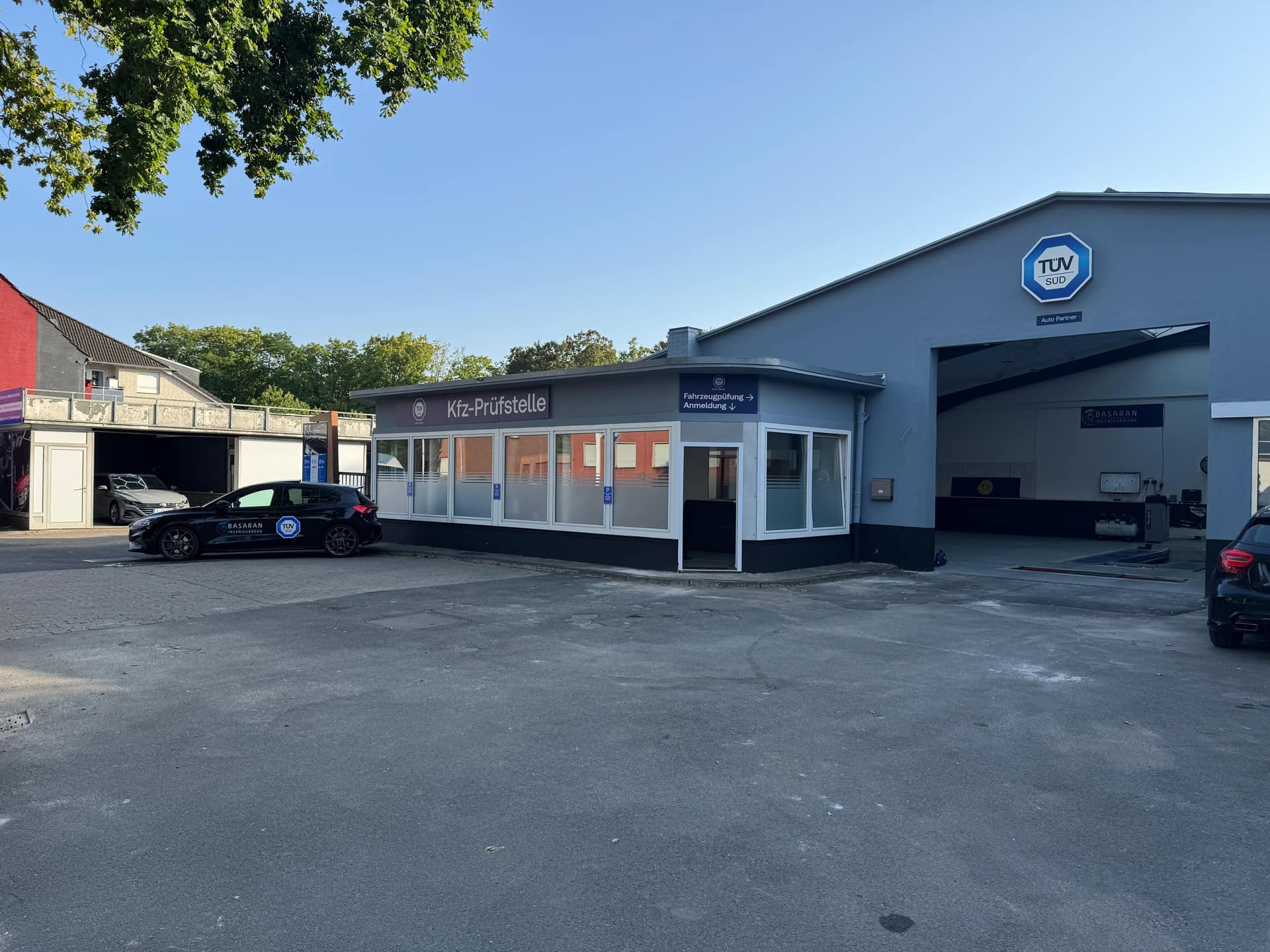 Betriebsgelände der Kfz-Prüfstelle Basaran in Ahlen mit Anmeldegebäude, offener Prüfhalle und Firmenfahrzeug